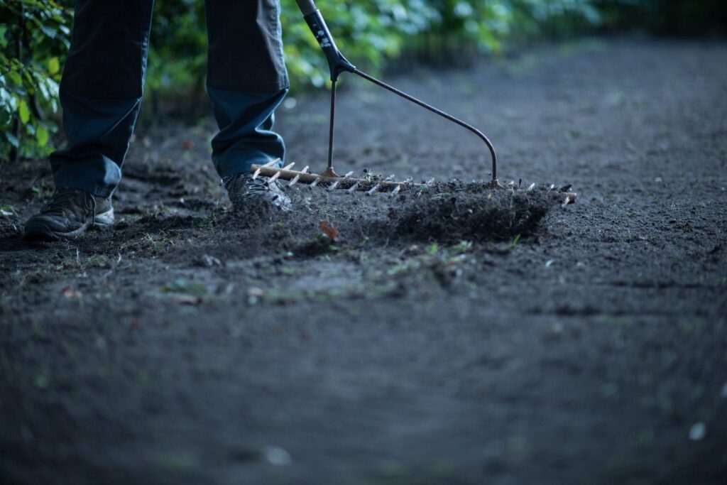 Close-up van handen die grond harken