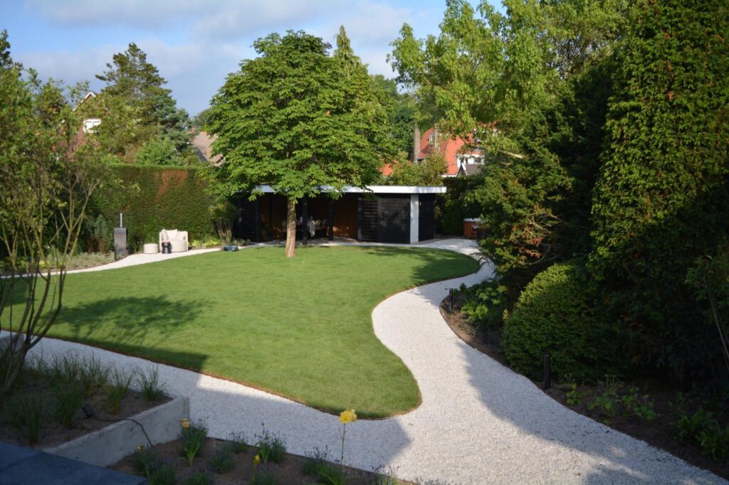 Achtertuin met strak gelegde graszoden en sierbestrating bij een veranda