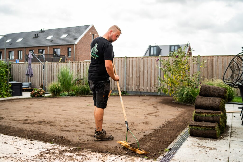Medewerker egaliseert de ondergrond zorgvuldig ter voorbereiding op het leggen van graszoden.
