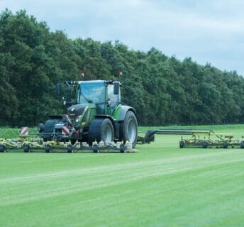 Een grote EcoClipper grasmaaier achter een tractor die duurzaam graszoden maait op een teeltveld