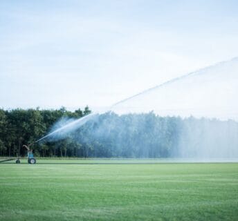 Beregeningshaspel sproeit water over een groot graszodenveld