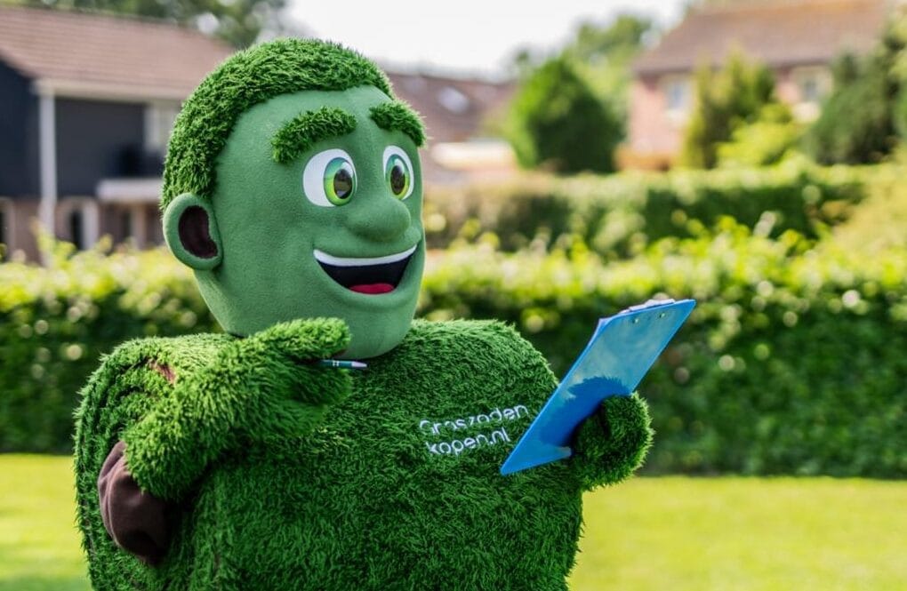 Mascotte Grasmattie met clipboard geeft tips voor het leggen van graszoden