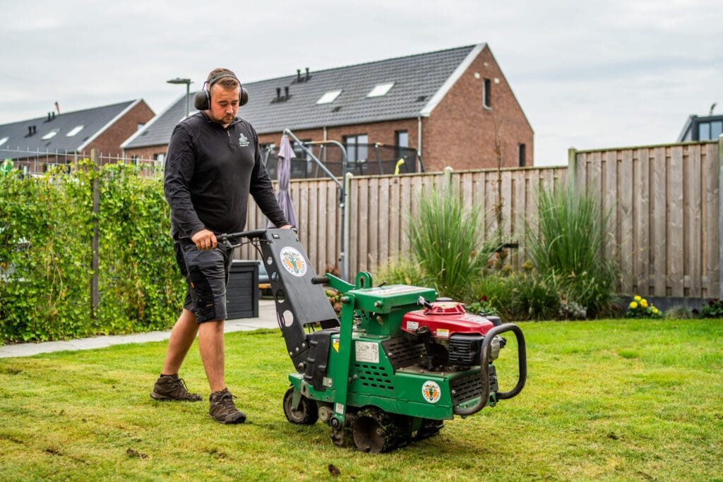 Medewerker van Graszodenkopen.be verwijdert oud gras met een snijmachine als voorbereiding op het leggen van nieuwe graszoden.
