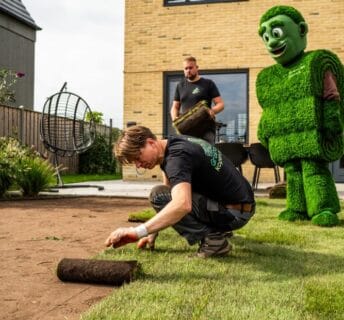 Mascotte van Graszodenkopen helpt bij het leggen van graszoden
