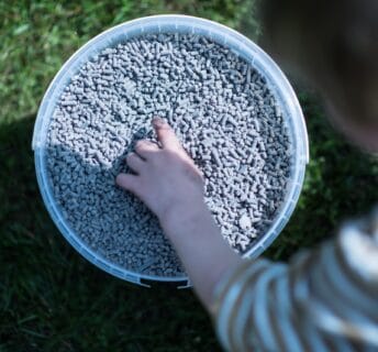 Kind pakt bemestingskorrels uit een bak voor het gazon